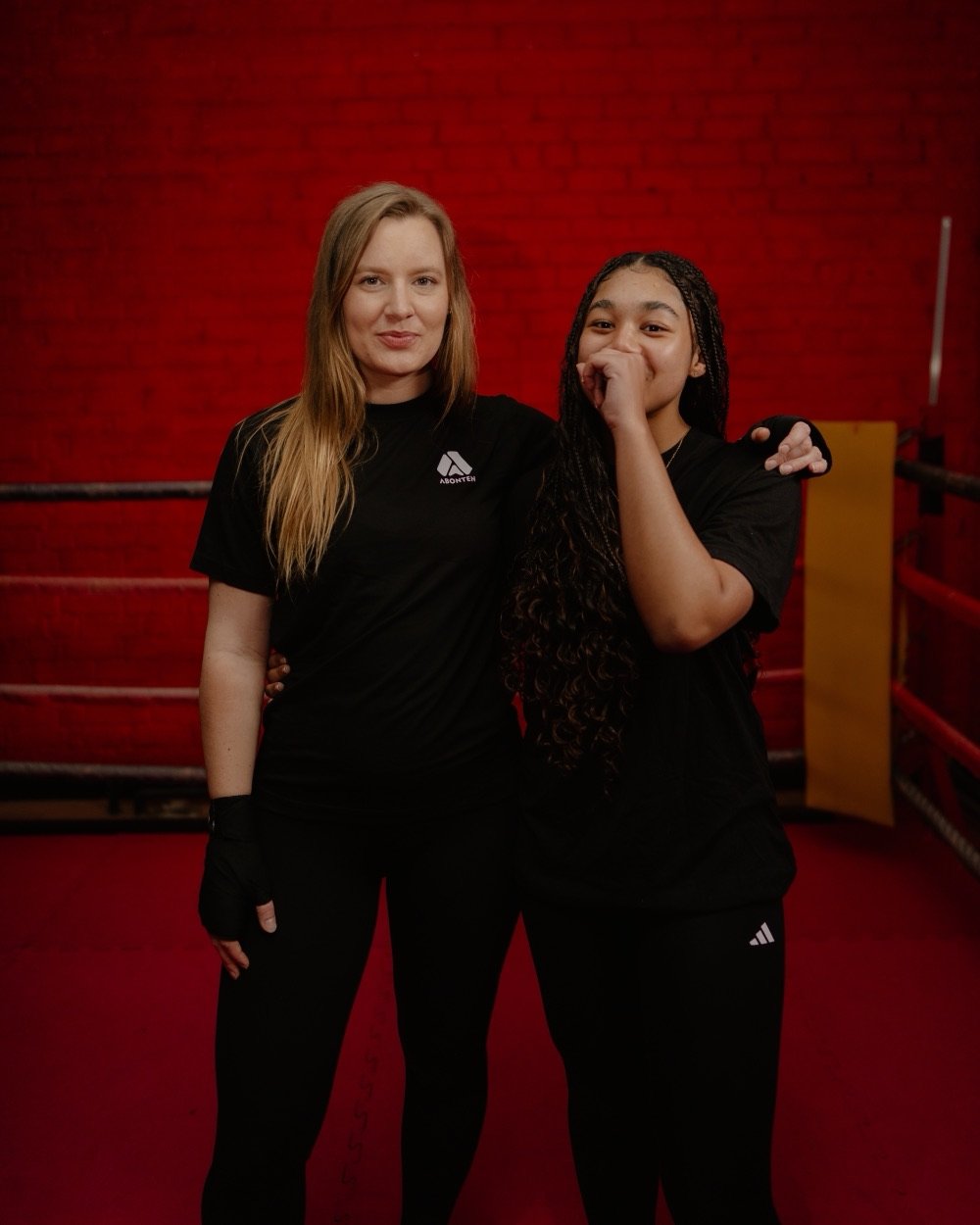 Two Abonten members smiling in the ring, one laughing behind her hand